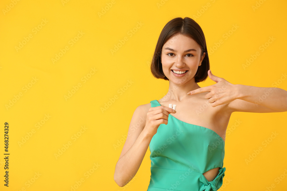 Young woman with chewing gum on color background