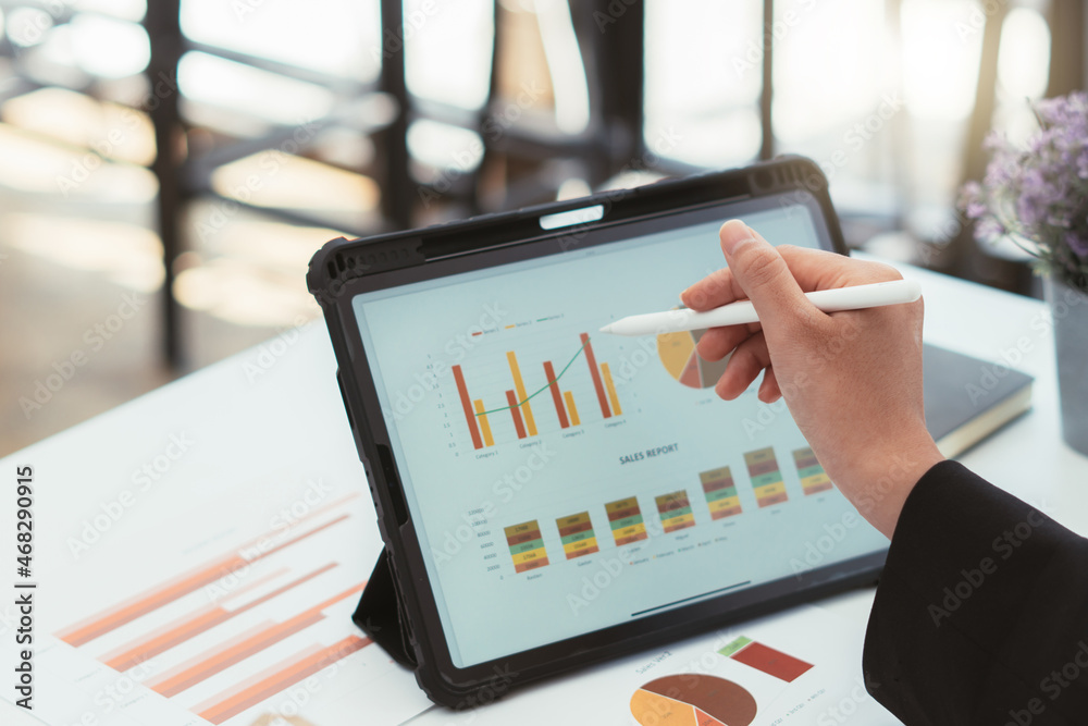 Business women using digital tablet with financial report spreadsheet on screen for business and mar