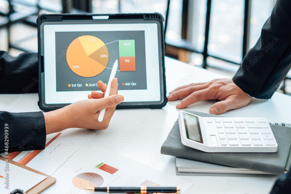 Two businessmen are together analyzing the financial data graph and pointing to the laptop computer 