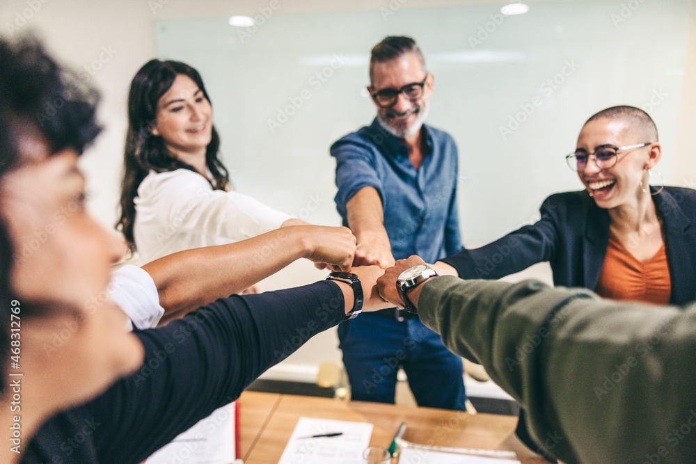 Happy group of businesspeople bringing their fists together in an office