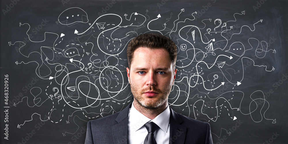 Portrait of handsome young european businessman on chalkboard wall background with arrows and though