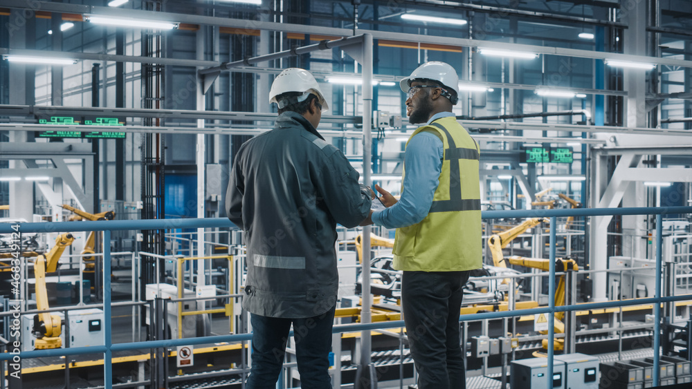 Multiethnic Manager and African American Car Factory Engineer in Uniform Using Tablet Computer. Auto