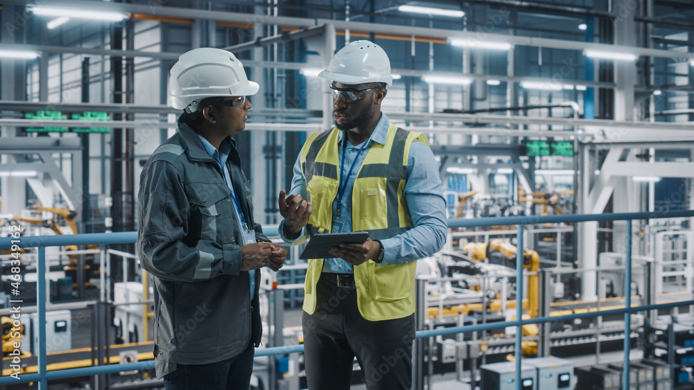 Multiethnic Manager and African American Car Factory Engineer in Uniform Using Tablet Computer. Auto