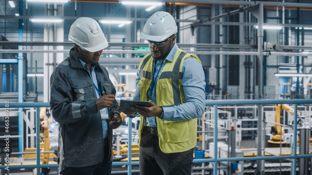 Multiethnic Manager and African American Car Factory Engineer in Uniform Using Tablet Computer. Auto