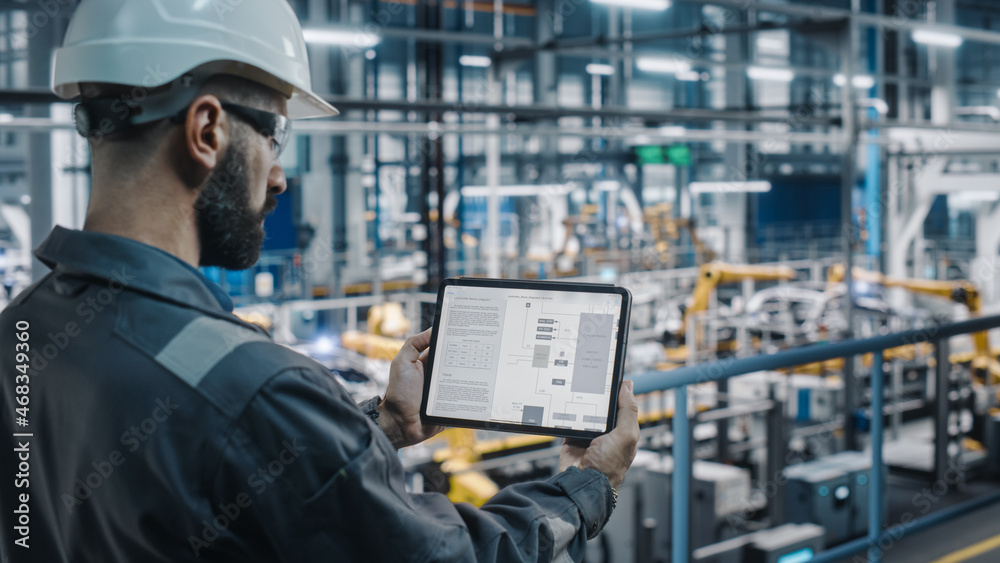 Car Factory Engineer in Work Uniform Using Tablet Computer with Electrical Blueprints and Schemes. M