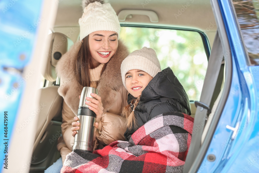 Happy mother and daughter sitting in car on winter day