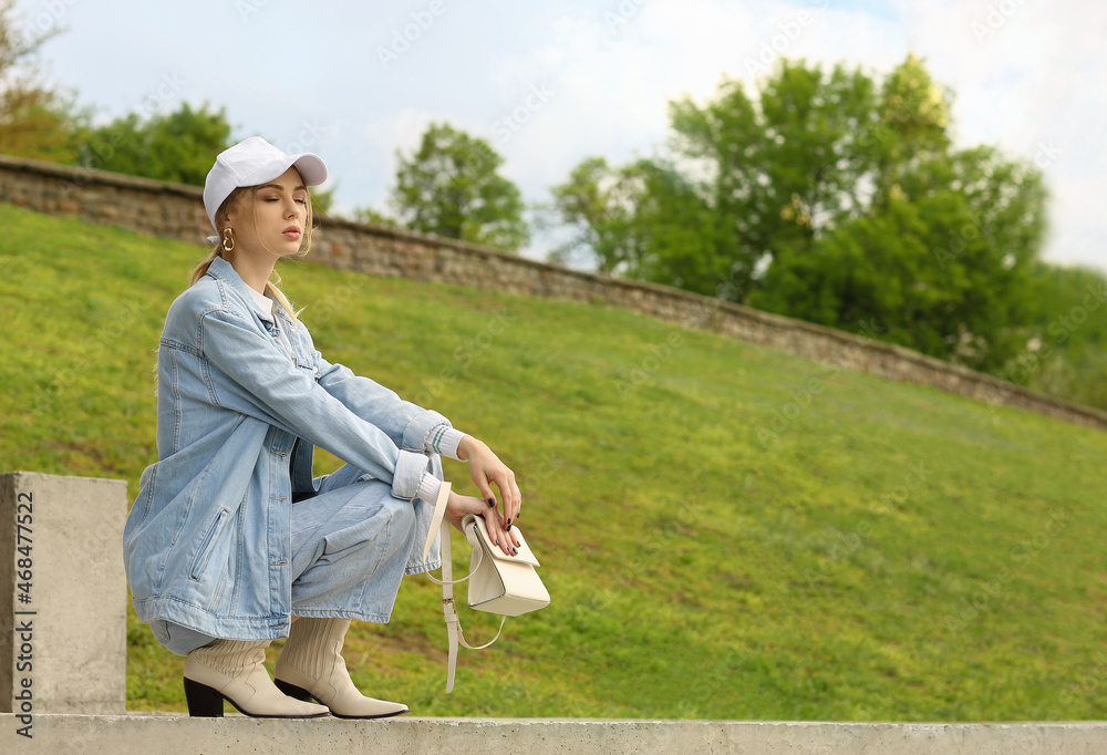 Young pensive woman in baseball cap squatting outdoors