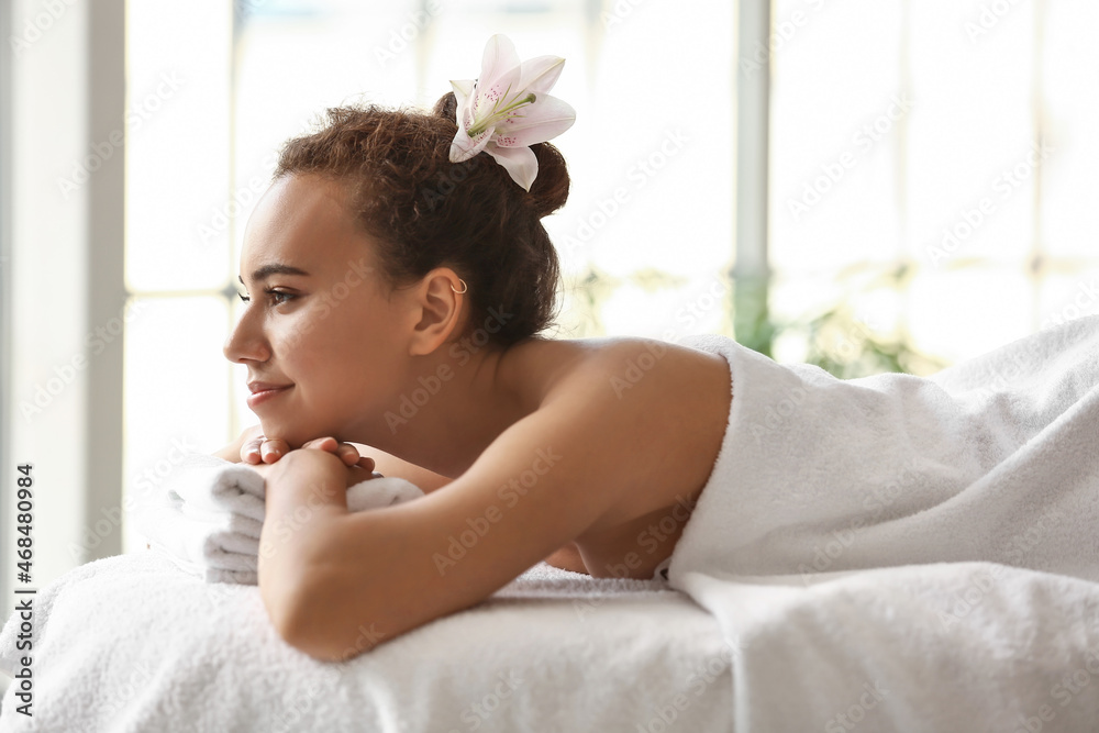 Young African-American woman lying on couch in spa salon