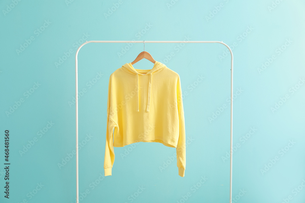 Rack with hoodie on color background