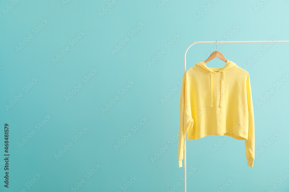 Rack with hoodie on color background