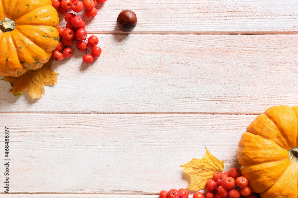 Beautiful autumn composition with ripe pumpkins and rowan berries on light wooden background