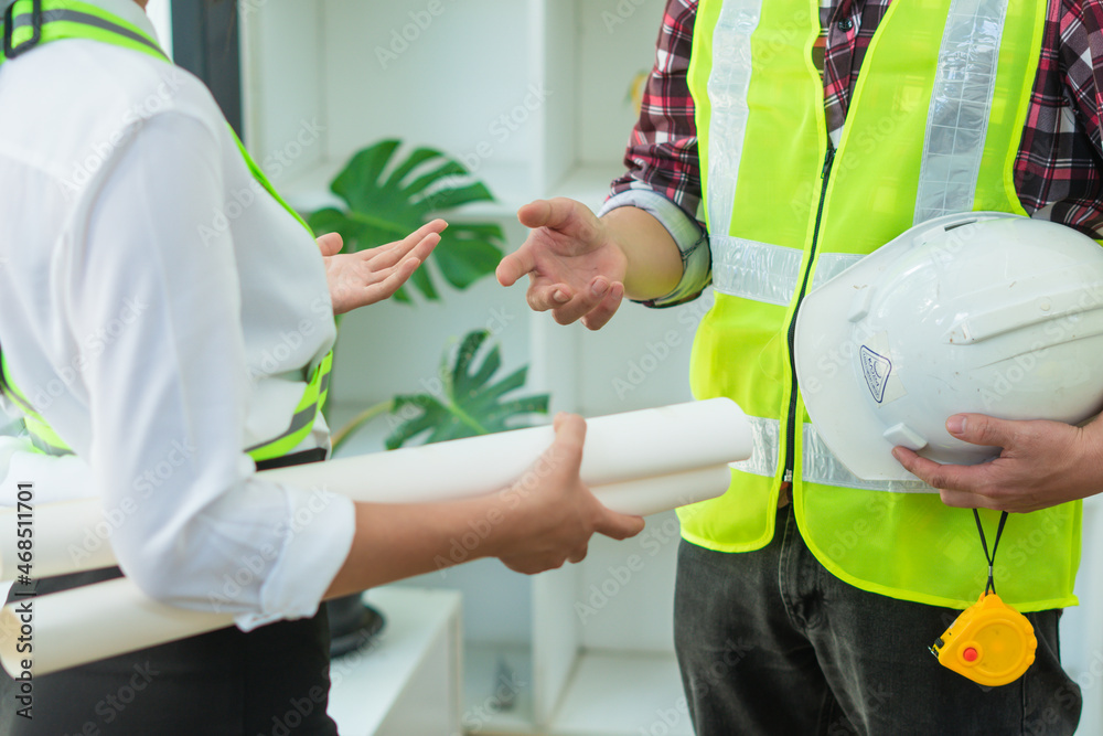 Management consulting with engineers working at construction site and holding blueprint in his hand 