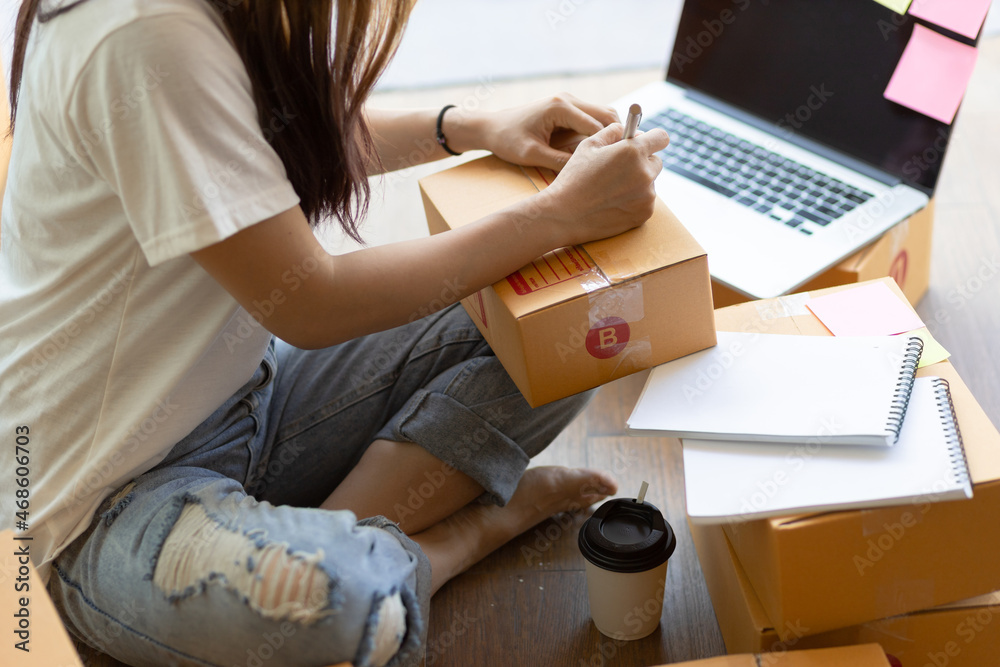 Woman who owns a small online business is writing customers addresses on parcels for shipping.