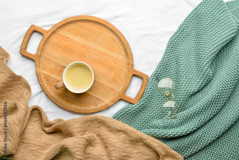 Wooden tray with cup of coffee and glasses on fabric background