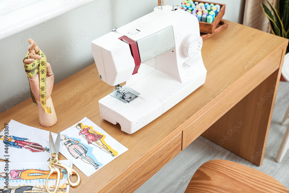 Modern sewing machine on wooden table in atelier