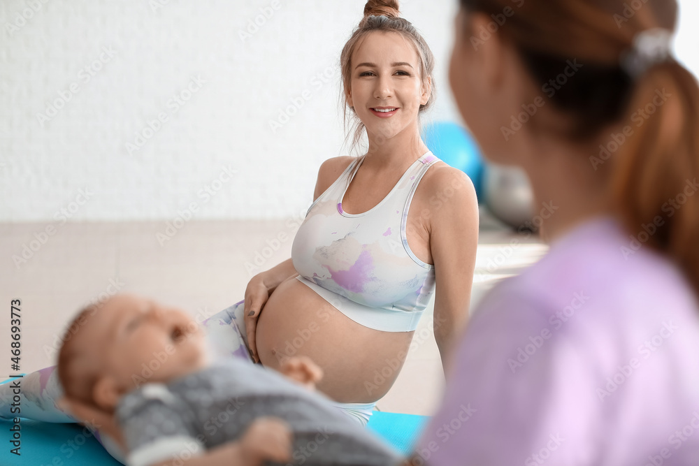 年轻孕妇带着教练和小婴儿在健身房