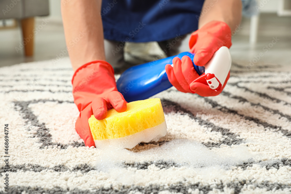 Young man cleaning carpet with sponge at home, closeup