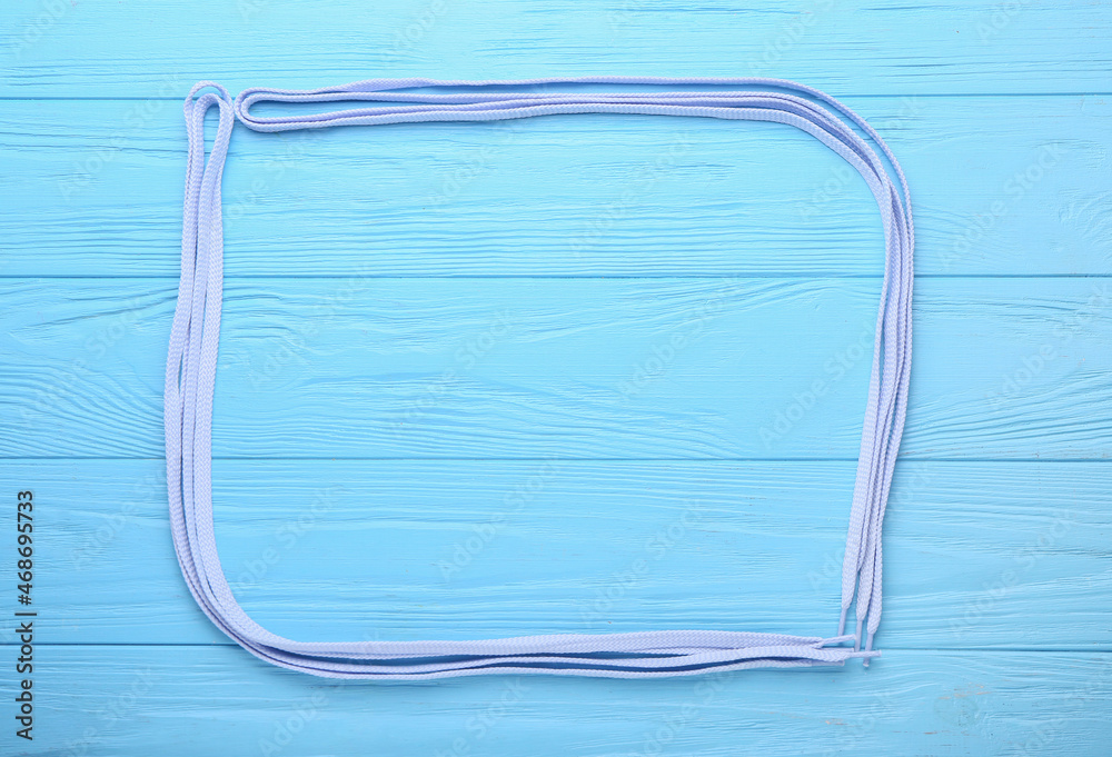 Frame made of shoe laces on color wooden background