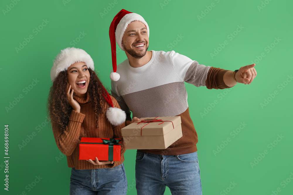 Happy couple with Christmas gifts on color background