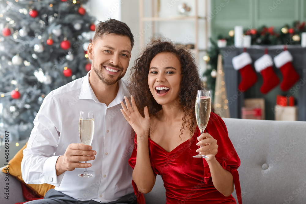 Happy couple with champagne celebrating Christmas at home