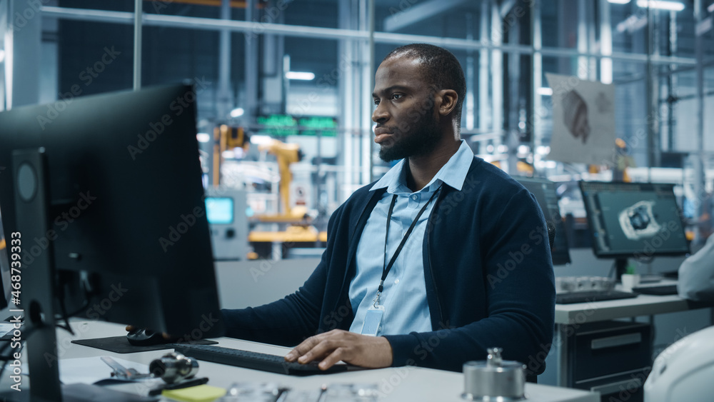 Car Factory Office: Portrait of Confident Black Male Chief Engineer Working on Desktop Computer. Pro