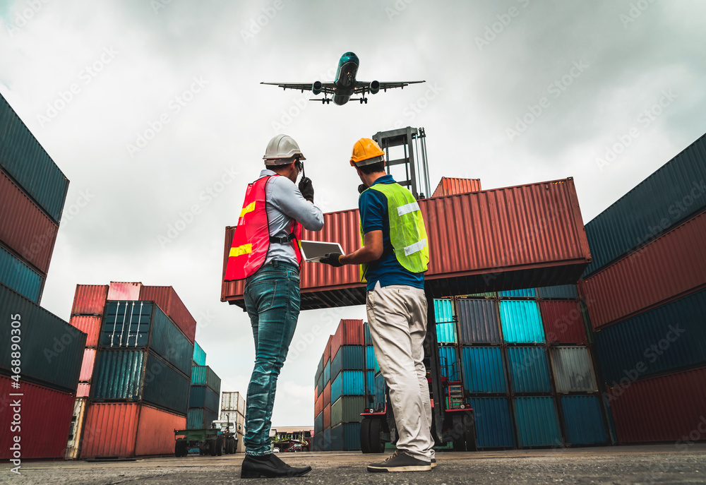 Industrial worker works with co-worker at overseas shipping container port . Logistics supply chain 