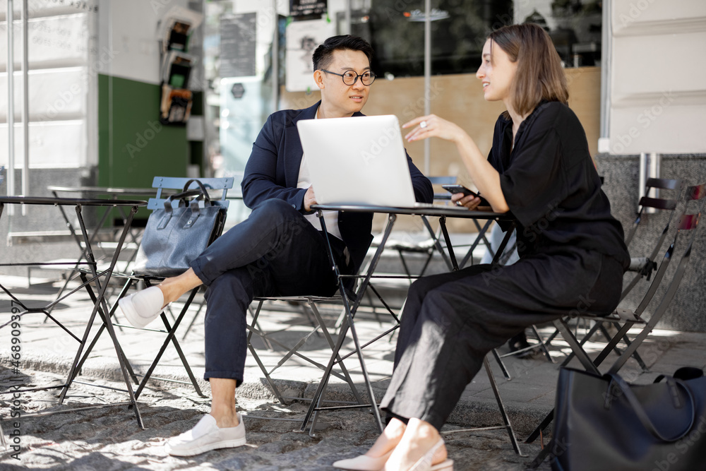 Multiracial business people watching something on laptop during work at outdoor cafe. Concept of rem