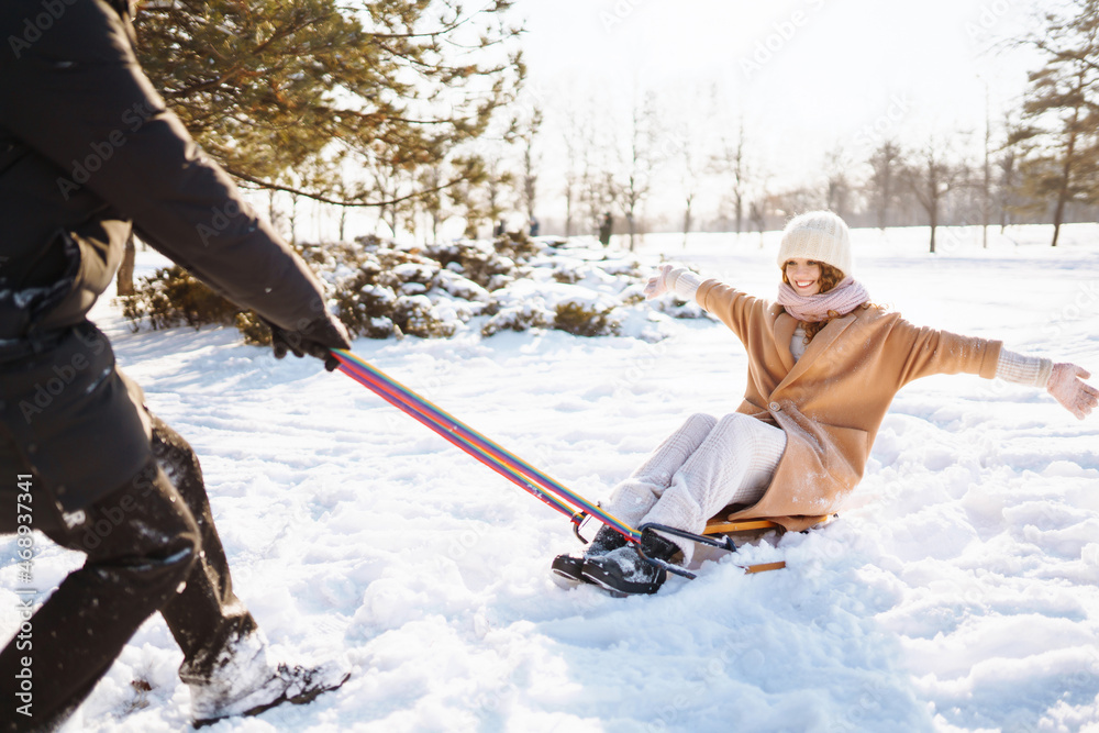 Happy woman  rolls  on a sled in the winter snowy forest. Сouple having fun in the winter nature. Ho