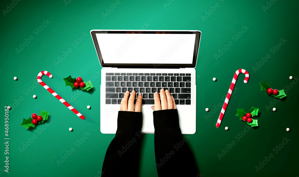 Person using a laptop computer with Christmas decorations from above