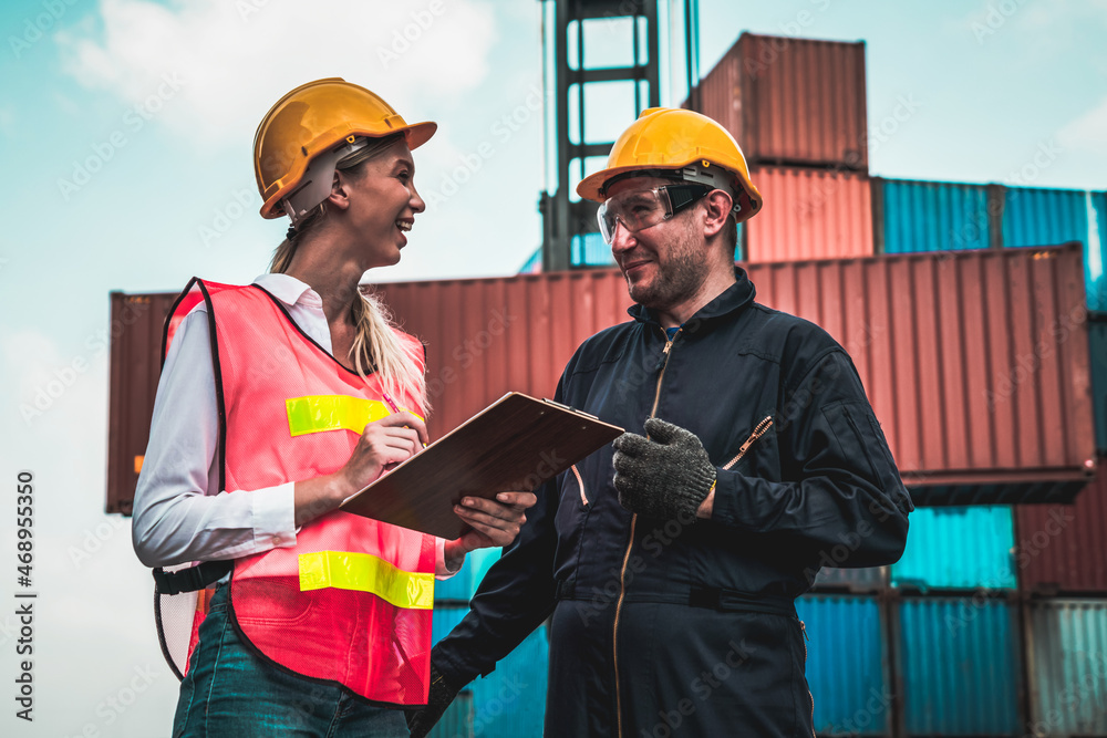 Industrial worker works with co-worker at overseas shipping container yard . Logistics supply chain 