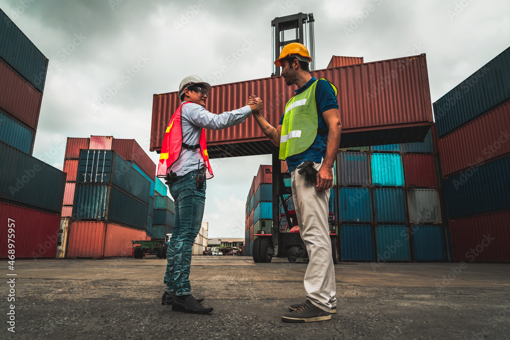 Industrial worker works with co-worker at overseas shipping container yard . Logistics supply chain 