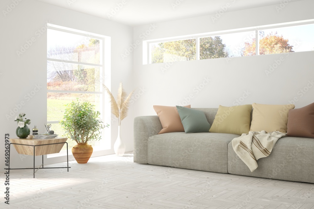 Stylish room in white color with sofa and autumn landscape in window. Scandinavian interior design. 