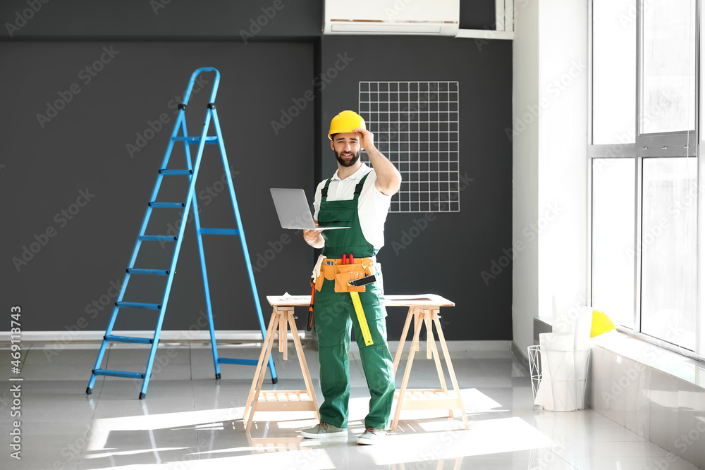 Construction worker with laptop in room