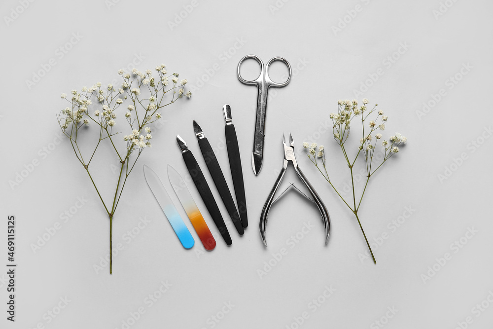 Manicure equipment and flowers on light background