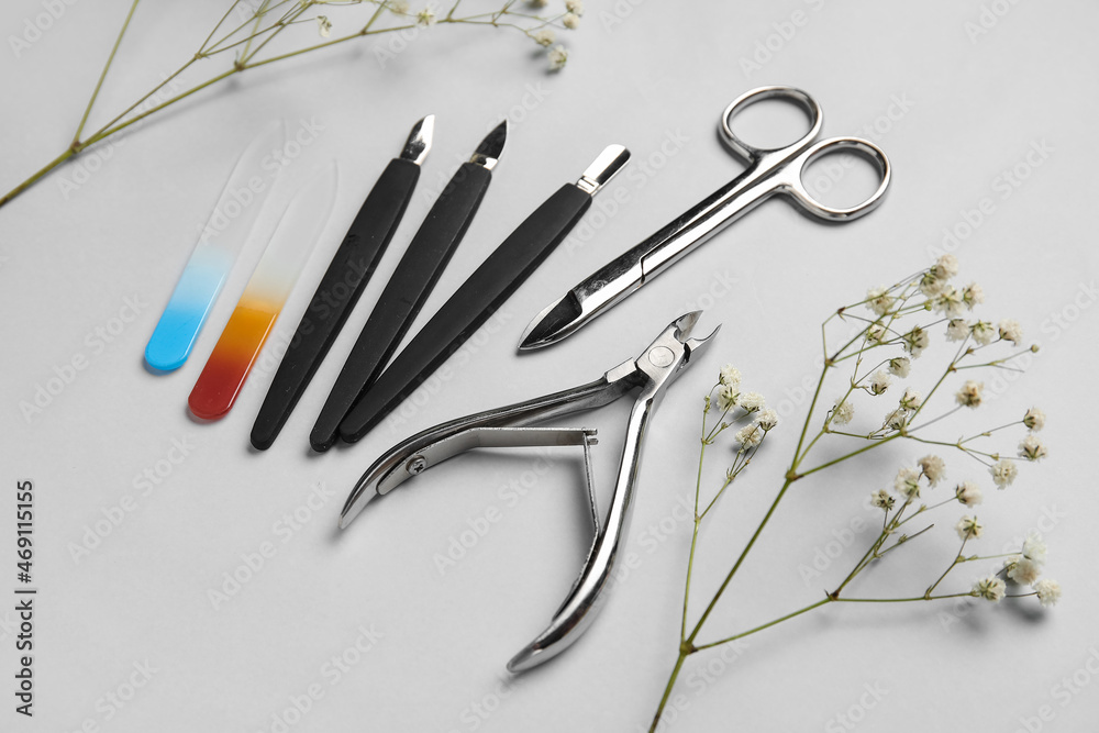 Manicure equipment and flowers on light background