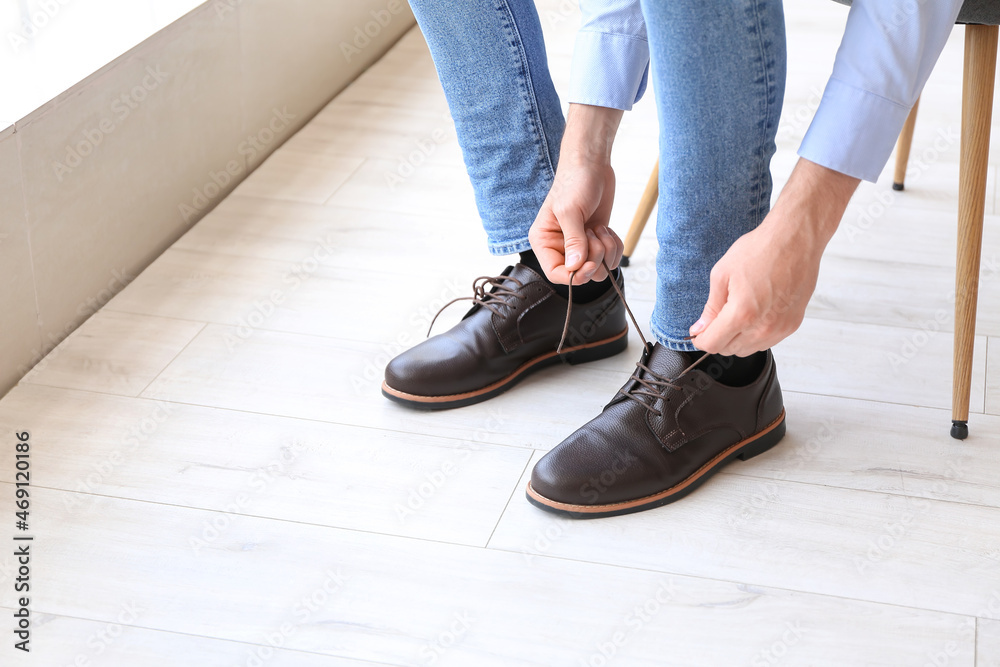 Man tying shoe laces at home, closeup