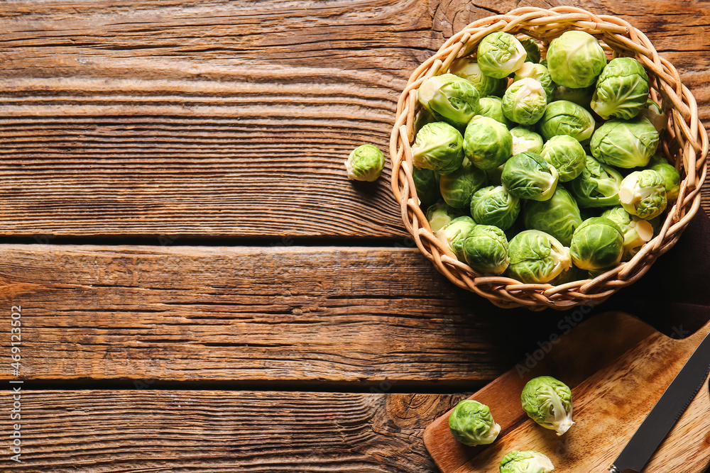 Wicker basket with fresh raw Brussels cabbage on wooden background