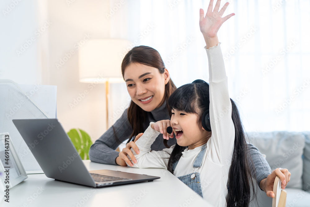 Asian little young girl kid learning online class at home with mother. 