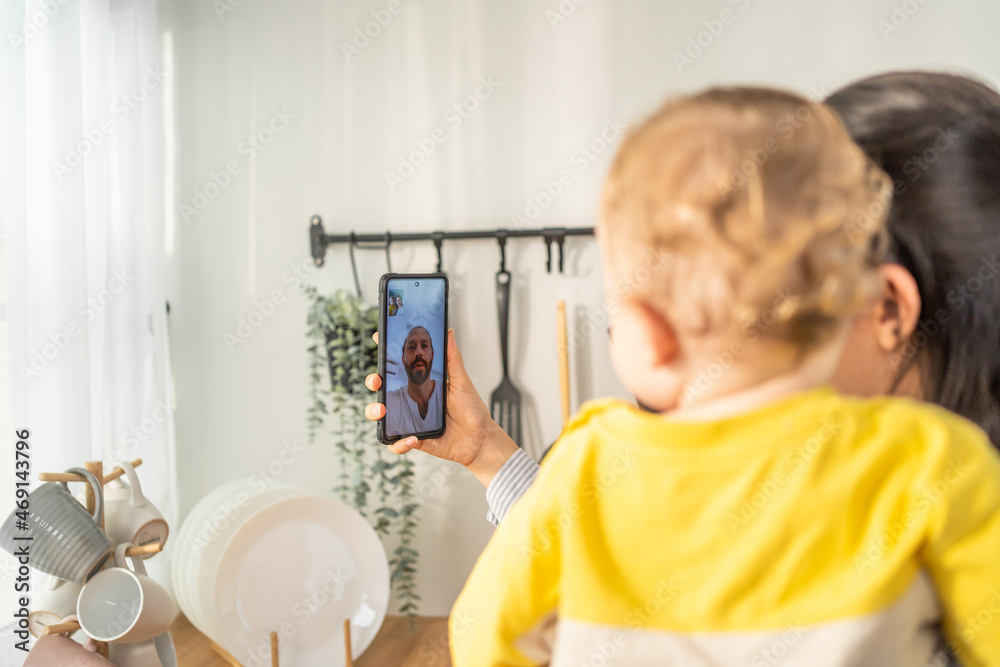 Caucasian mother holding little baby and video call online with family