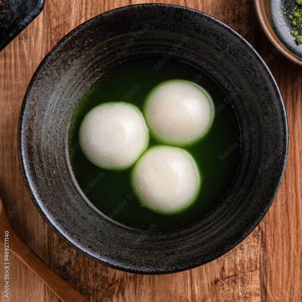 Matcha big tangyuan and matcha soup on wooden table.