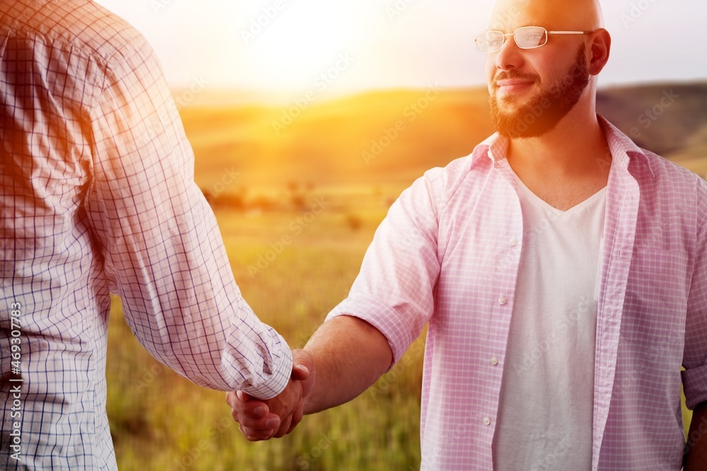 Male farmers handshake outdoor on a field