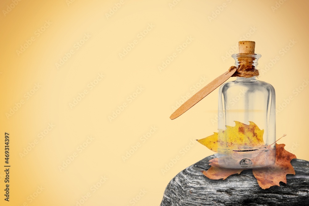 cosmetic oil in a jar with a dropper on a stone with leaf. Autumn theme.