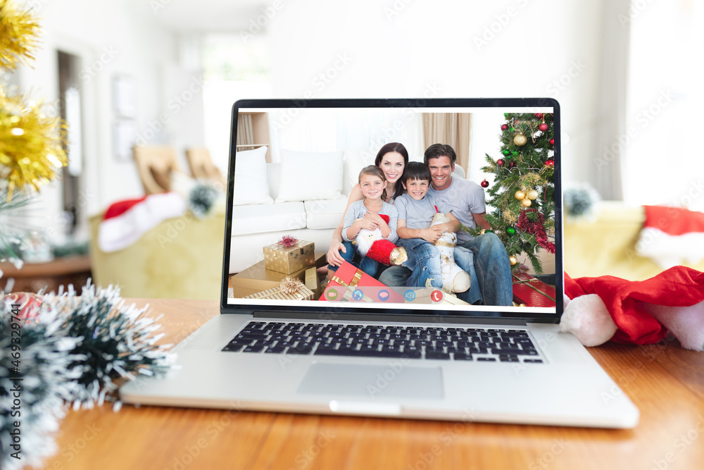 Happy caucasian family smiling on laptop video call screen at christmas time