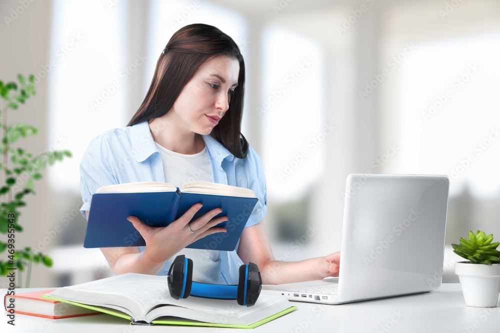 Smiling woman listening educational online lecture, writing notes