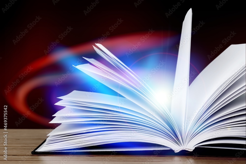 Magical image of open book over wooden table with glitter lights