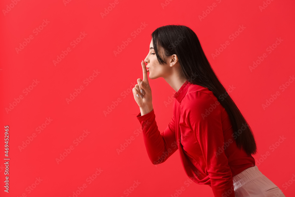 Young woman showing silence gesture on color background