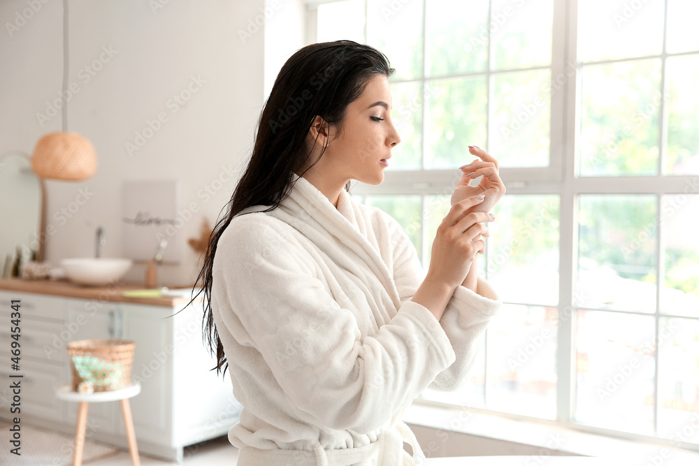 Pretty young woman in bathrobe after taking bath at home