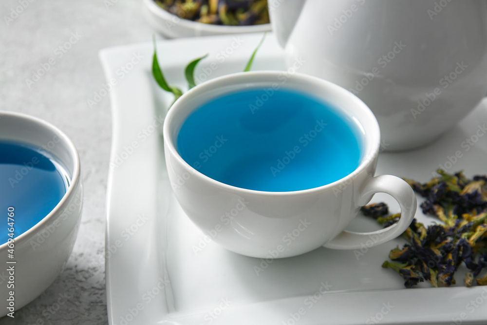 Cup of organic blue tea and dried flowers on table, closeup