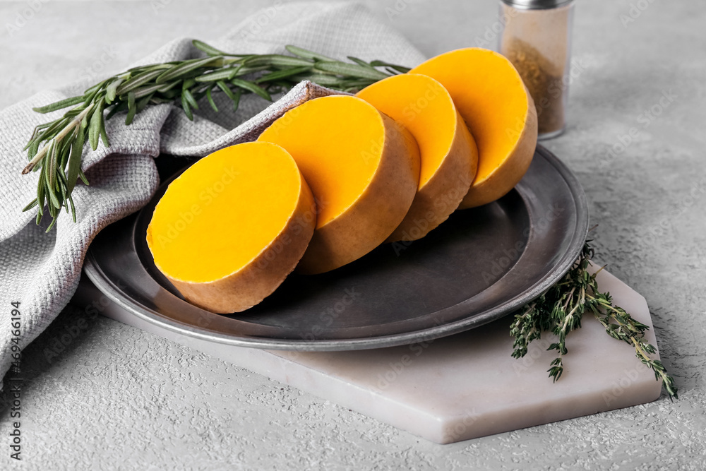 Plate with fresh pumpkin pieces on light background