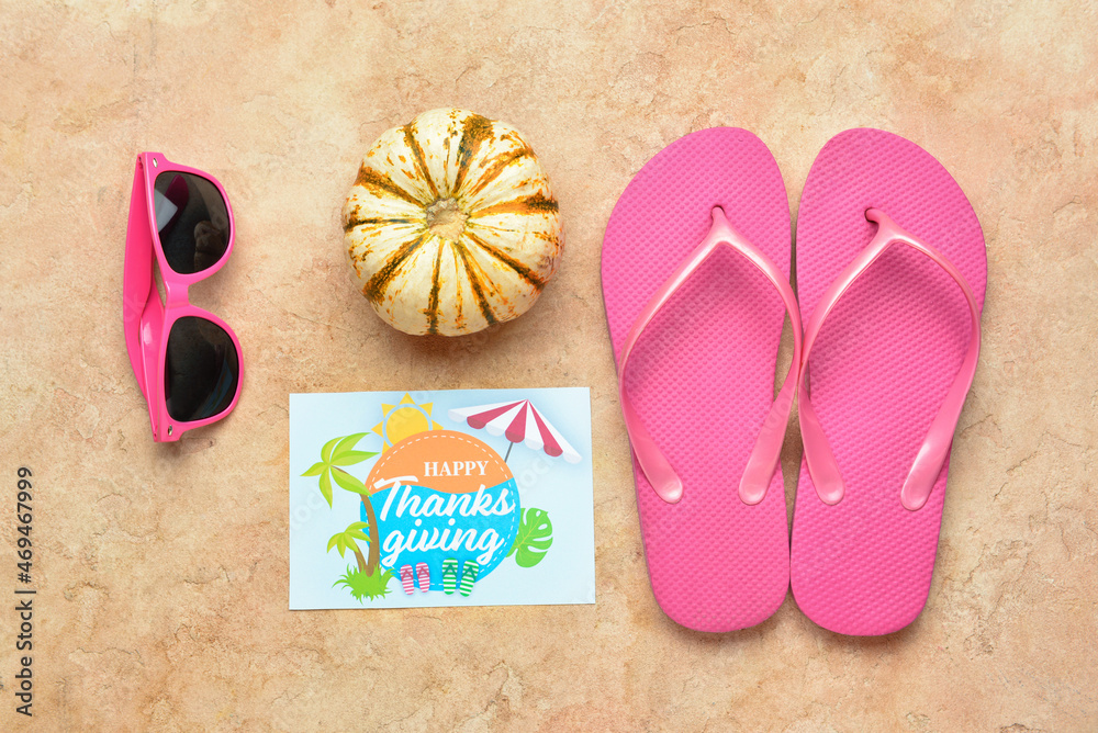 Sunglasses, pumpkin, flip flops and paper card with text HAPPY THANKSGIVING on color background